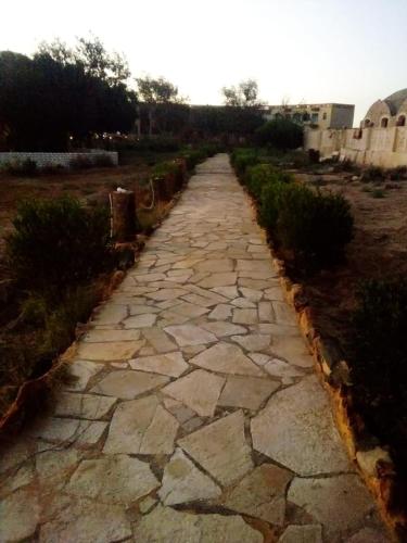 a stone path in a field next to a building at oasis panorama in Bawiti