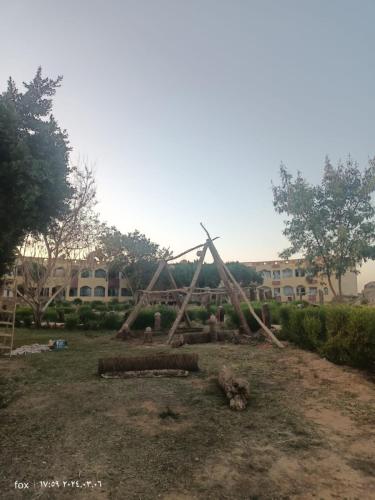 a pile of logs in a yard with a building at oasis panorama in Bawiti
