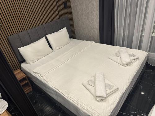 Una cama con sábanas blancas y toallas. en Mrt Rain Suite en Lara