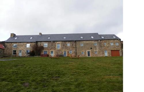 ein großes Backsteingebäude mit zwei Bänken auf einem Feld in der Unterkunft The Farmhouse in Durham