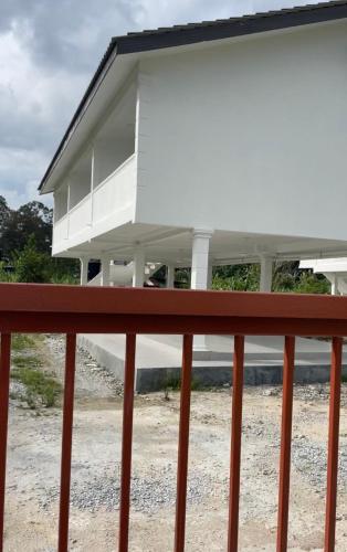 a white house with a red railing at home stay harith & humaira in Lengging