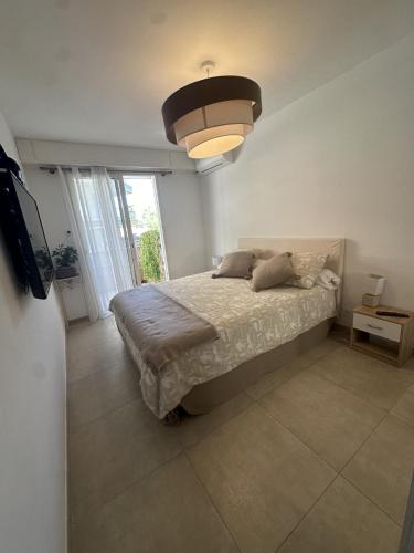 une chambre avec un lit et une grande fenêtre dans l'établissement Bel appartement, sans mauvaises surprises, à Juan-les-Pins