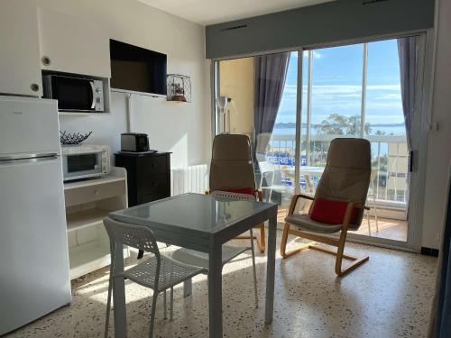 La cuisine est équipée d'une table, de deux chaises et d'un réfrigérateur. dans l'établissement Bel appartement T1 avec vue dégagée, loggia, ascenseur et wifi à Balaruc-les-Bains - FR-1-553-102, à Balaruc-les-Bains