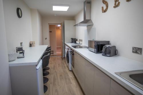a large kitchen with white counter tops and a sink at Quite and comfortable Eastbourne in Eastbourne