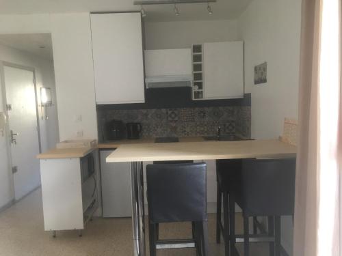 a kitchen with white cabinets and bar stools at Appartement T2 in Six-Fours-les-Plages