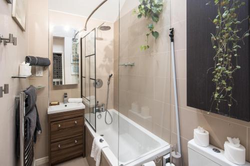 a bathroom with a shower and a tub and a sink at Kennington 3BR Haven: Dog-Friendly/Central London in London