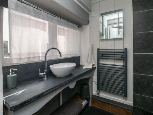 baño con lavabo blanco y ventana en An Skyber, en Penzance