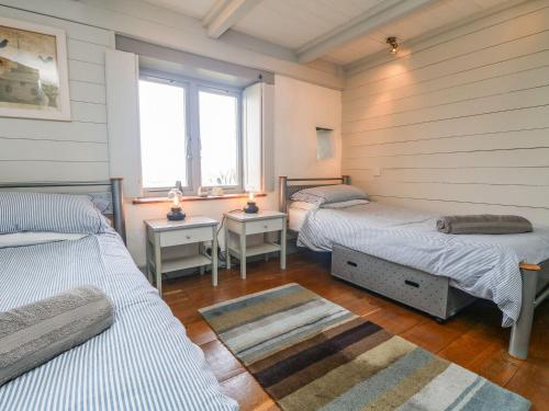 Dos camas en una habitación con dos ventanas. en An Skyber, en Penzance