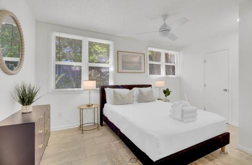a white bedroom with a bed and two windows at Live Oak by AvantStay Walk to Folly Beach in Folly Beach