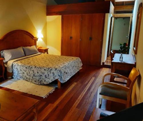 a bedroom with a bed and a chair in it at Acea do Bubal in Os Peares
