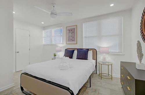 a white bedroom with a large bed with blue pillows at Red Maple by AvantStay Walk to Folly Beach in Folly Beach