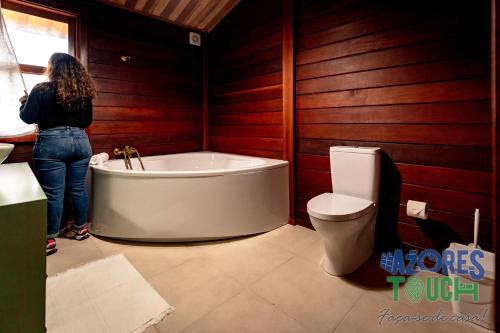 a woman standing next to a bath tub in a bathroom at Casa da Fontinha in Praia da Vitória