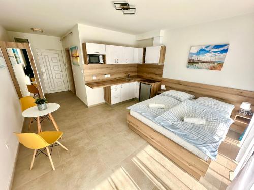 a bedroom with a bed and a table and a kitchen at Ady Corner Prémium Apartmanok - Siófok in Siófok