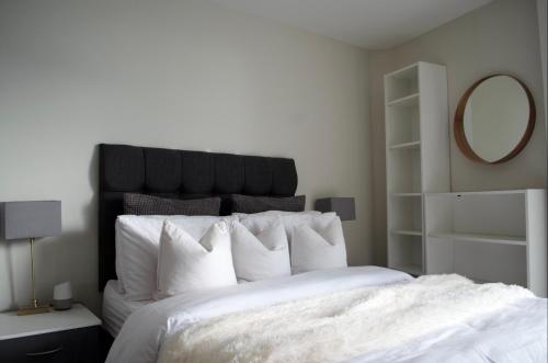 cama blanca con cabecero negro y espejo en 1 Bedroom Apartment in Central Manchester, en Mánchester