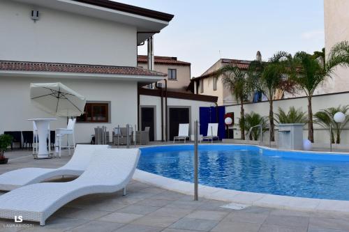 una piscina con sillas y una sombrilla junto a un edificio en Hotel Riviera Azzurra, en Oliveri