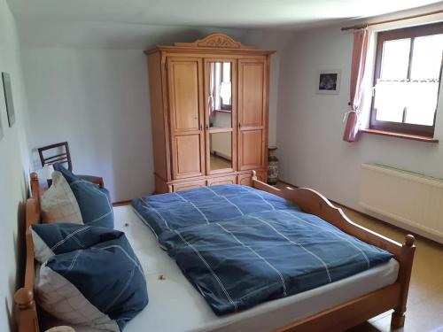 Schlafzimmer mit einem blauen Bett und einem Holzschrank in der Unterkunft Ferienhaus Harz in Allrode