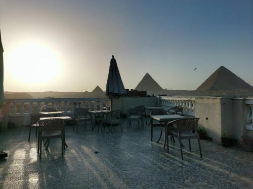 a patio with tables and chairs with pyramids in the background at Pyramid stars inn in Cairo