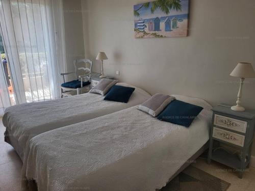 une chambre avec deux lits et une chaise et une fenêtre dans l'établissement Appartement pieds dans le sable au Parc de Cavalaire - Climatisé - FR-1-100-248, à Cavalaire-sur-Mer