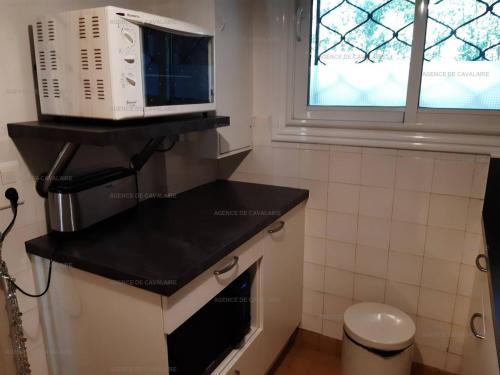 un micro-ondes posé sur un comptoir dans une cuisine dans l'établissement Appartement pieds dans le sable au Parc de Cavalaire - Climatisé - FR-1-100-248, à Cavalaire-sur-Mer