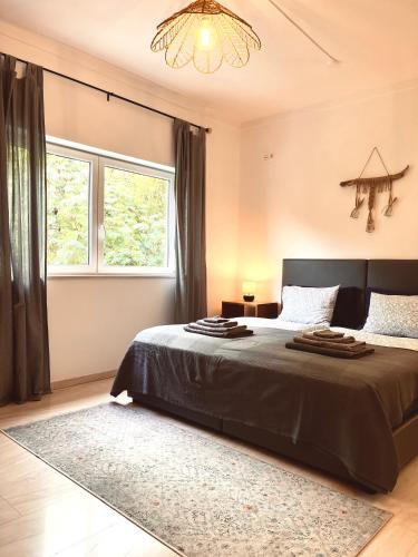 a bedroom with a bed and a window and a chandelier at Edles Apartment in Architektenvilla mit großem Pool, Sauna, Dachterrasse und malerischem Garten in Pataias