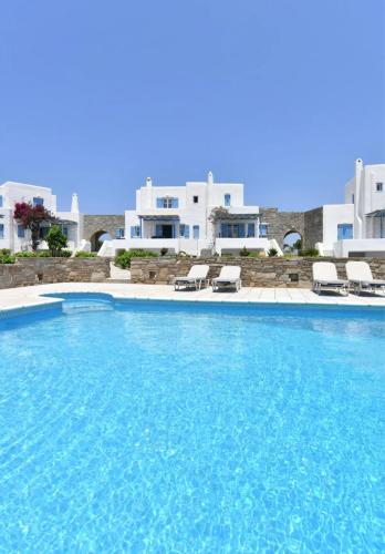 a large swimming pool with chairs and buildings in the background at Villa Galano PAROS GREECE in Ambelas