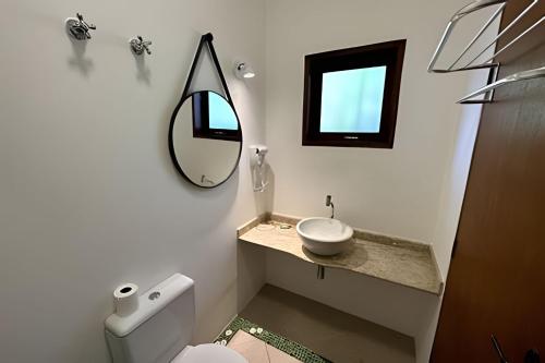 a white bathroom with a sink and a mirror at Vila Saíra, chalé Laranja, 50m da praia in Ilhabela