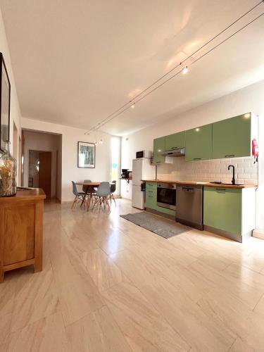 a large kitchen with green cabinets and a table at Edles Apartment in Architektenvilla mit großem Pool, Sauna, Dachterrasse und malerischem Garten in Pataias