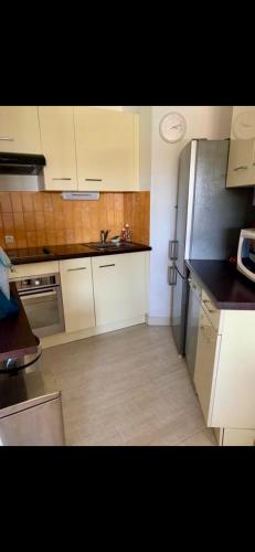 une cuisine avec des armoires blanches et un réfrigérateur en acier inoxydable dans l'établissement Cosy unoverlooked apartment with swimming pool, à Mandelieu-la-Napoule