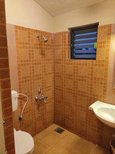 a bathroom with a shower with a sink and a toilet at Haven Guest House in Kodaikānāl