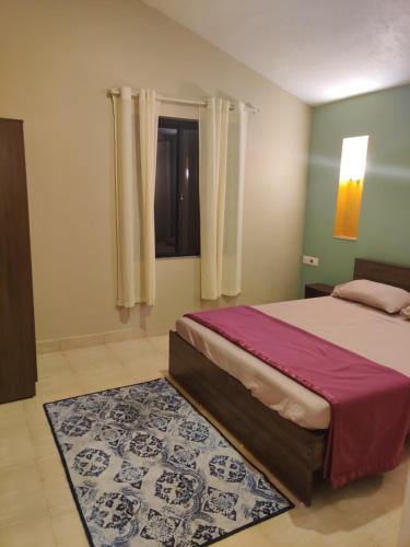 a bedroom with a bed and a window and a rug at Haven Guest House in Kodaikānāl