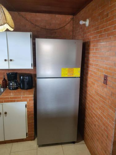 a stainless steel refrigerator in a kitchen with a brick wall at Casa de Campo, frente a la playa Skybluebyguanche in Colón