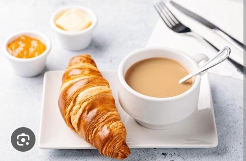 a plate with a cup of coffee and a croissant at Dubai Homes near ADCB METRO STATION in Dubai