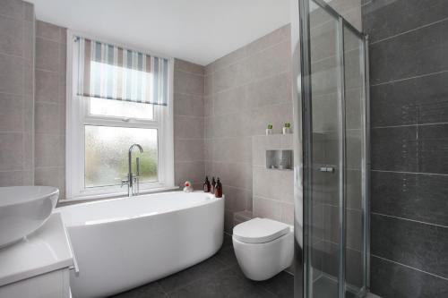 ein Badezimmer mit Badewanne, Toilette und Waschbecken in der Unterkunft Sea Salt Cottage - Mins to beach & shops Dog Friendly in Deal