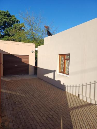 a white building with a garage and a window at Leipoldt street 3 in Clanwilliam