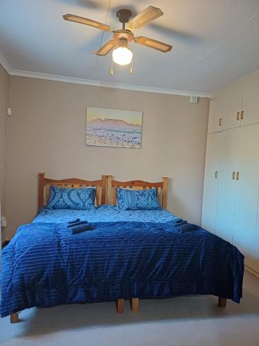 a bedroom with a blue bed with a ceiling fan at Leipoldt street 3 in Clanwilliam