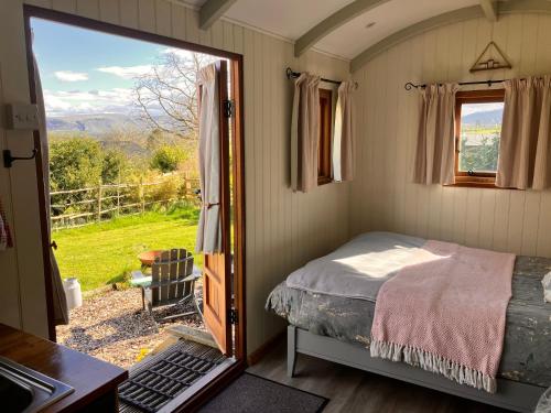 um pequeno quarto com uma cama e uma janela em Archie the shepherd’s hut em Penruddock
