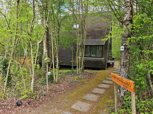 a sign in front of a cabin in the woods at Het Hertenbos chalet 136 in Durbuy