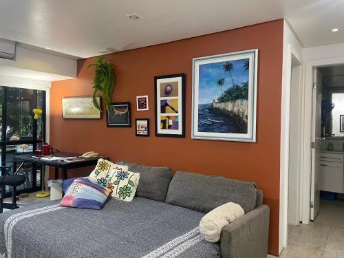 a living room with a gray couch and an orange wall at Flat encantador no Atlantic Towers in Salvador