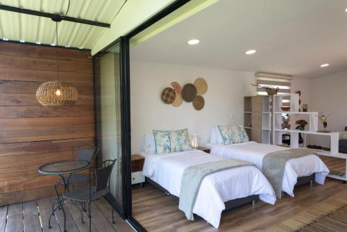 1 dormitorio con 2 camas, mesa y pared de cristal en San Felipe Lodge. Birding and Wellness, en Cali