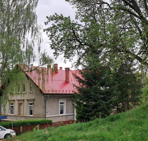 an old house with a red roof on a hill at Przy pałacu in Bozkow
