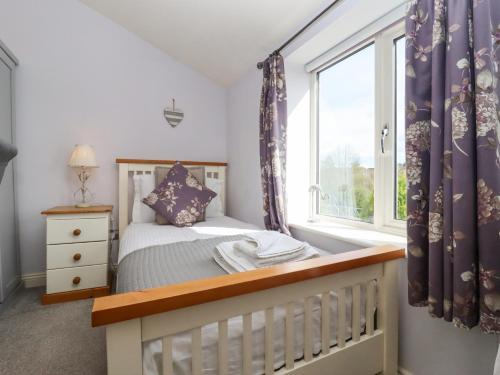 a bedroom with a crib and a window at The Tack Room in Lydney