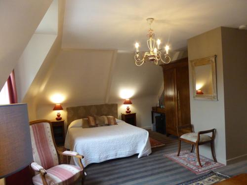 a bedroom with a bed and two chairs and a chandelier at Le Clos du Pont Martin in Saint-Briac-sur-Mer