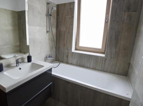 bagno con lavandino, vasca e finestra di Lux Apartament Bacău a Bacău