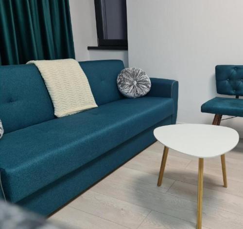 Lux Apartament Bacău في باكاو: أريكة زرقاء وطاولة في غرفة المعيشة
