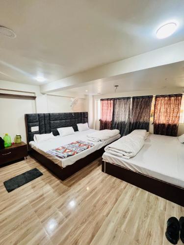 two beds in a room with wooden floors at Hotel Shankar Gaura Palace in Ujjain