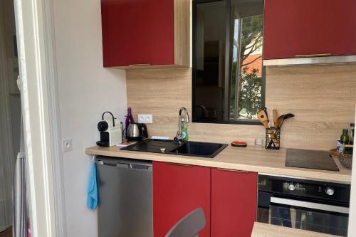 une cuisine avec des armoires rouges et un évier dans l'établissement Pretty cocoon with two balconies, à Arcachon
