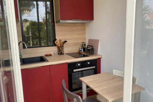 La cuisine est équipée de placards rouges, d'un évier et d'une table. dans l'établissement Pretty cocoon with two balconies, à Arcachon