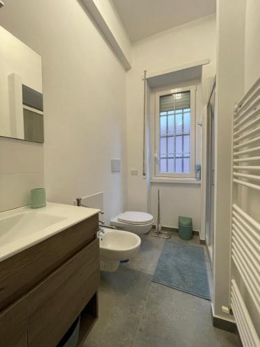 a white bathroom with a toilet and a sink at Maison Cristina in Lido di Ostia