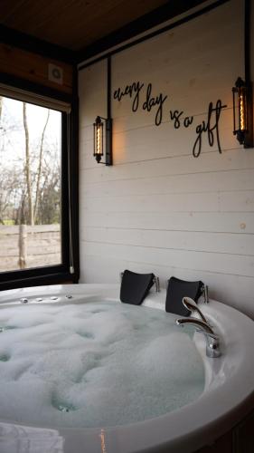 a bathroom with a bath tub with a happy day sign on the wall at Pentalow Cabin in Kocaeli