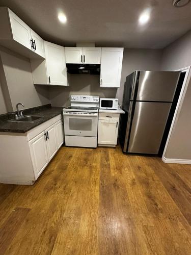 uma cozinha com armários brancos e um frigorífico de aço inoxidável em Budget To Go Room- All amenities near by!! K2 em Kitchener